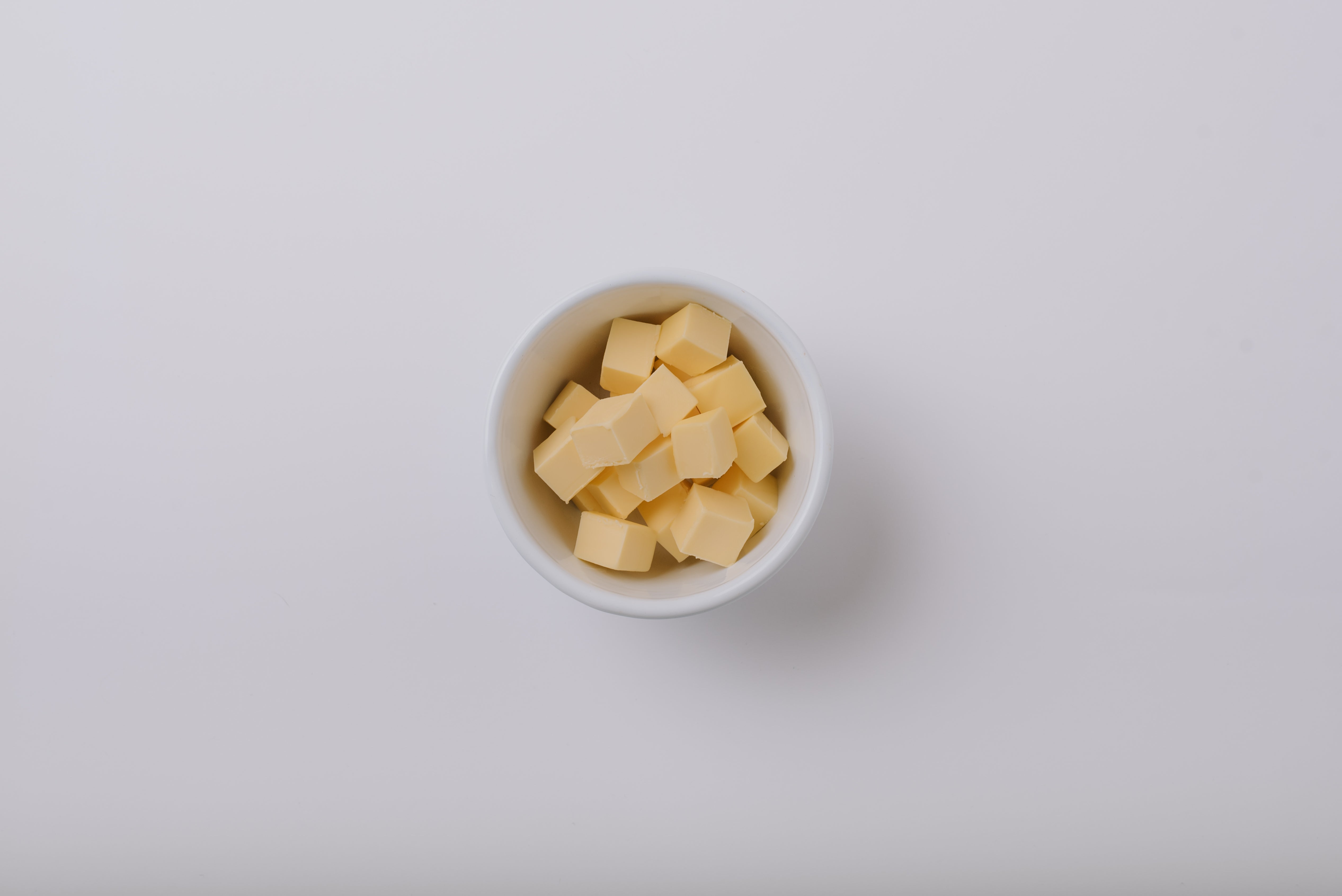 Small white bowl filled with margarine on a light grey background