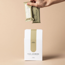 Hand holding a Apple Crumble Lila Jasmine milk support lactation bars against a beige background