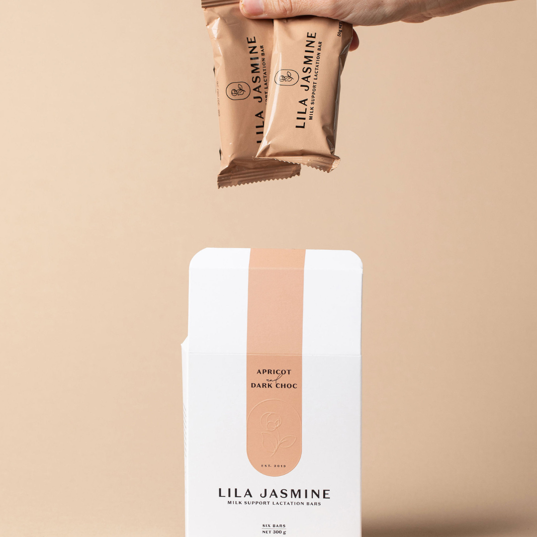 Hand holding two Lila Jasmine apricot and chocolate bars against a beige background