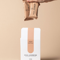 Hand holding two Lila Jasmine apricot and chocolate bars against a beige background