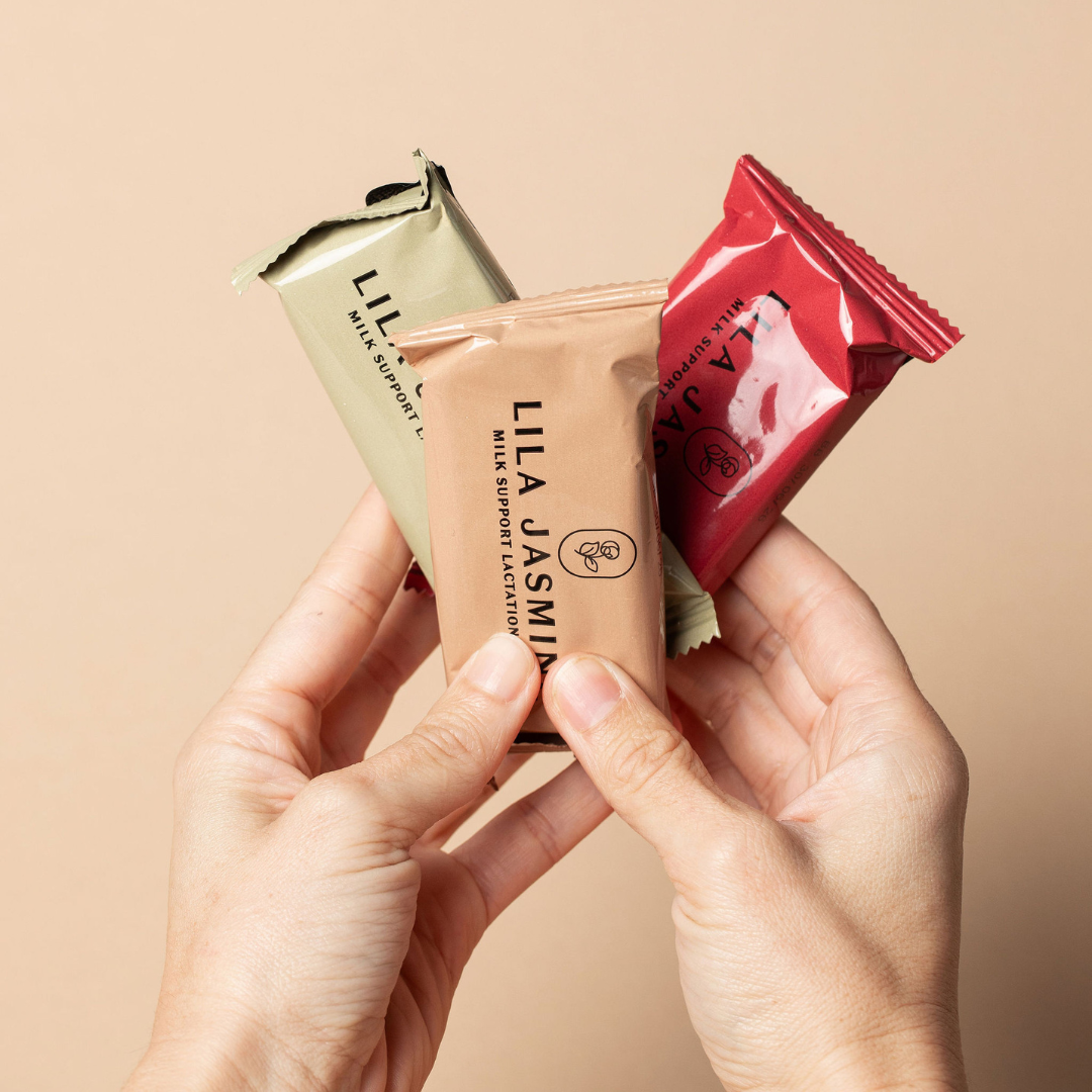 Three Lila Jasmine milk support lactation bars held by hands against a beige background