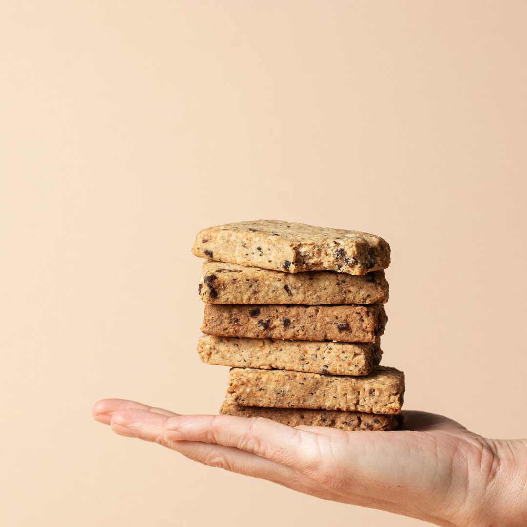 Stack of Lila Jasmine milk support lactation bars held in a hand against a beige background
