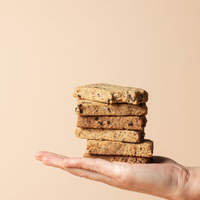 Stack of Lila Jasmine milk support lactation bars held in a hand against a beige background