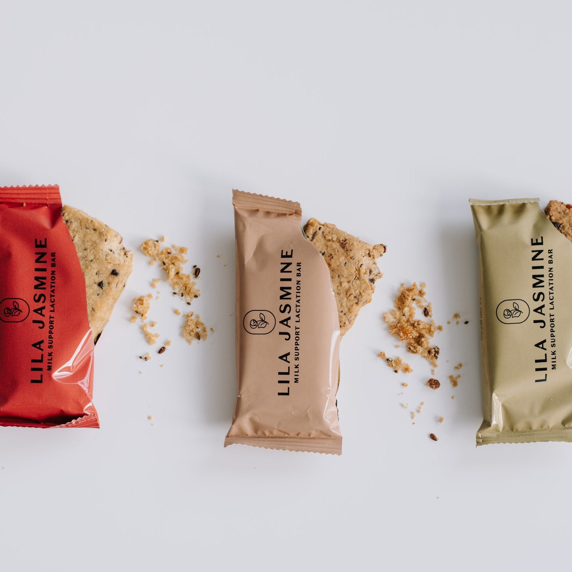 Lila Jasmine Mix of Six lactation bar bundle, featuring two bars of each flavour: mixed berry, apricot and dark chocolate, and apple crumble, designed to support breastfeeding mums. Opened, crumbled lactation bar. 